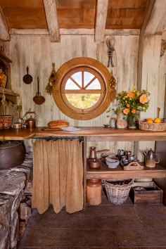 an old fashioned kitchen with lots of pots and pans on the stove top in front of a round window