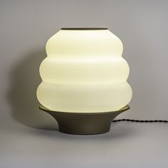 a white lamp sitting on top of a table next to a black corded charger