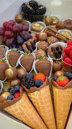 chocolate covered strawberries, raspberries, and other treats are in ice cream cones