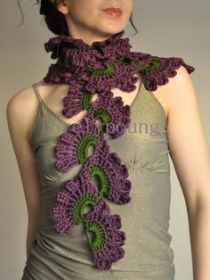 a woman wearing a purple and green crocheted scarf with leaves on it's neck