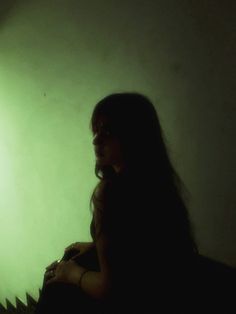 a woman sitting in front of a green light