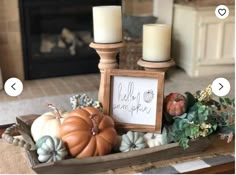 a wooden tray filled with pumpkins and candles