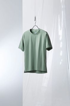 a green t - shirt hanging on a clothes line in front of a white wall