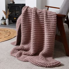 a crocheted blanket sitting on top of a rug next to a wooden chair