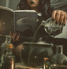 a woman sitting on the floor reading a book while holding an empty glass pitcher in her hand