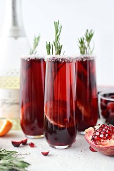 two glasses filled with red liquid and garnished with rosemary