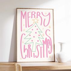 a white vase sitting on top of a wooden table next to a christmas tree poster