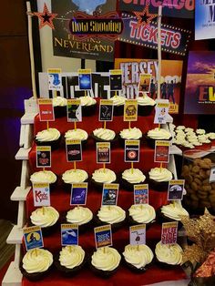 cupcakes are arranged on red velvet with white frosting and signs that spell out the names of movies