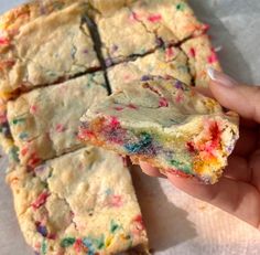 a person holding a piece of cake with sprinkles