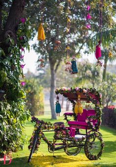 a pink bike decorated with flowers and hanging decorations in the back seat is parked under a tree