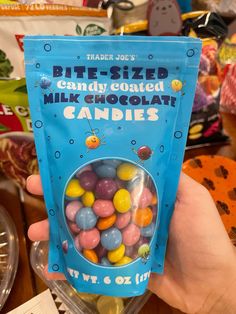 a hand holding a bag of candy coated milk chocolate candies