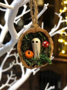 an ornament hanging from a tree decorated with fake mushrooms and pumpkins is shown