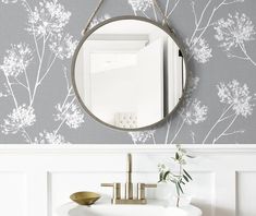 a white sink sitting under a round mirror next to a wall mounted faucet