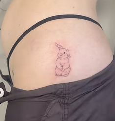 a woman's stomach with a small bunny tattoo on it