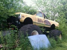 a truck that is in the grass with big tires on it's back end