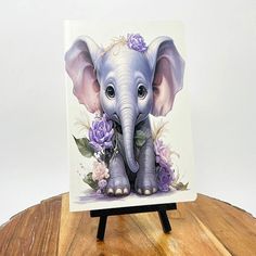 an elephant with purple flowers on it's head is standing on a wooden stand