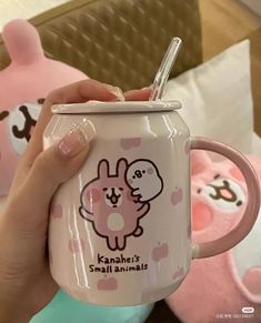 a person holding up a pink mug with a bunny on the front and heart shaped handles