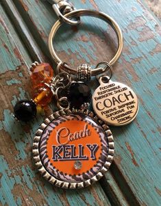 an orange coach keychain is sitting on a wooden bench with beads and charms