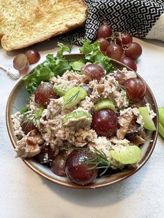 a plate with grapes, bread and salad on it