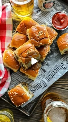 several sliders and beer on a table with napkins, glasses and sauces