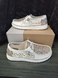 a pair of white shoes with gold sequins on the bottom, and a box behind them