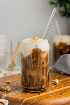 an iced drink with whipped cream and caramel is on a cutting board next to other drinks