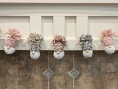 several knitted items are hanging on a line in front of a fireplace mantel