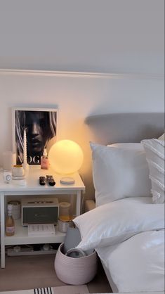 a bedroom with white bedding and pillows on top of the bedspread, next to a night stand