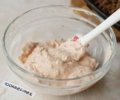 a glass bowl filled with food and a white spoon in the bowl next to it