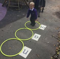 three children are playing with hula hoops on the ground