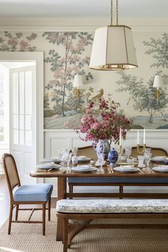 the dining room table is set with blue and white china, candles, and flowers