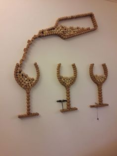 three wine glasses made out of wooden pegs are hanging on the wall next to each other