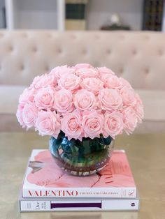 a vase filled with pink roses sitting on top of a book