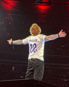 a man standing on top of a stage with his arms outstretched