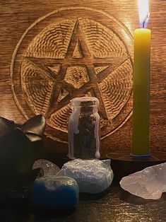 various crystals and a candle sitting on a table with a pentagramil in the background