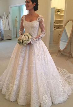 a woman in a white wedding dress standing next to a mirror and holding a bouquet