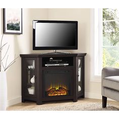 an entertainment center with a flat screen tv on top of it and a fire in the fireplace