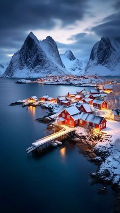 an aerial view of a small village in the middle of water with mountains in the background