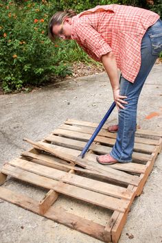 a woman is bending over on a wooden pallet