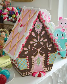 a decorated gingerbread house sitting on top of a white mantle next to other decorations