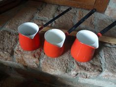 three orange cups sitting on top of a brick wall next to two black and white baseball bats