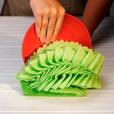 a person is cleaning a red plate with green ruffles on the table top