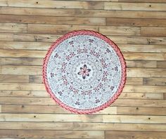 a red and white round rug sitting on top of a wooden floor next to a wall