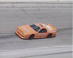 an orange race car driving on a track with the number 25 on it's side