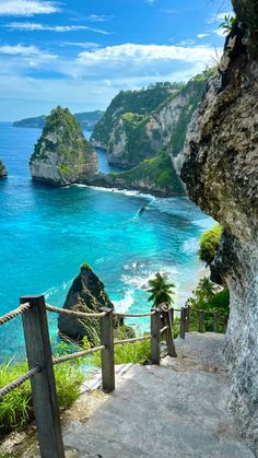 stairs lead down to the blue water and sandy beach with cliffs in the background at nusa penida island, philippines