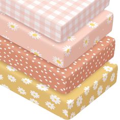 four different colored boxes stacked on top of each other with daisies all over them