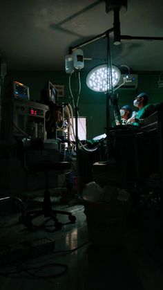 an operating room with lights and medical equipment in the dark, while two doctors are working on their laptops