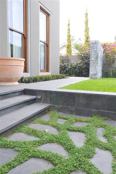 a house with grass growing on the ground and steps leading up to it's front door