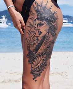 a woman's leg with a tattoo on it and an ocean in the background