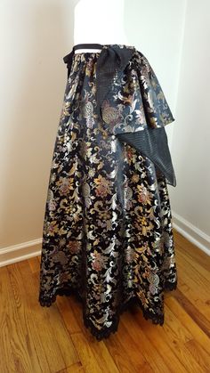 "This one of a kind statement-making ball skirt is very versatile and can be worn for many occasions, such as weddings, proms, Renaissance faires, and Steampunk events. It is made of luxurious Chinese satin brocade in hues of black, gold, red and purple with a scalloped edge lace hemline. The Chinese characters woven into the fabric translate to \"longevity and prosperity\" Please note that this skirt is pictured with a crinoline underneath which is not included. The skirt can easily accommodate Elegant Skirt With Traditional Drape For Evening, Elegant Evening Skirt With Traditional Drape, Fitted Skirt With Traditional Drape For Evening, Fitted Traditional Drape Skirt For Evening, Fitted Evening Skirt With Traditional Drape, Evening Long Skirt With Attached Cancan, Traditional Floor-length Evening Skirt, Traditional Evening Floor-length Skirt, Elegant Party Skirt With Traditional Drape